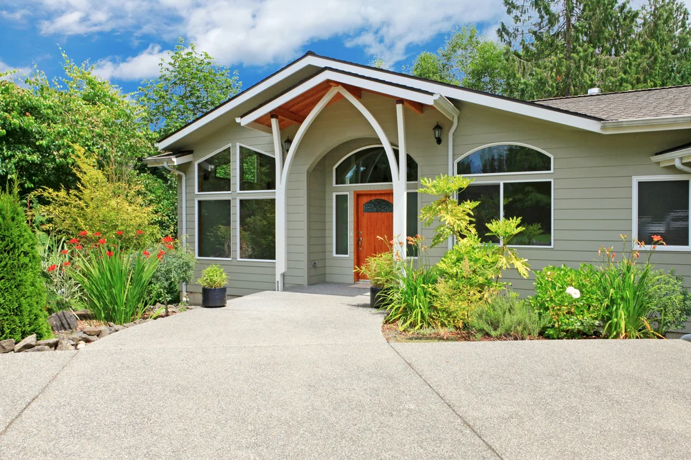 Modern green home exterior with wooden door and concrete driveway